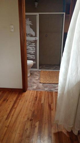 a bathroom with a toilet and a room with a wooden floor at El Corral in Cuenca