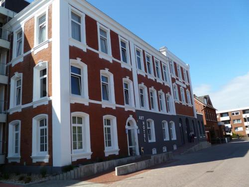 a red brick building with white windows on a street at Rodehuus Wohnung 2 in Borkum