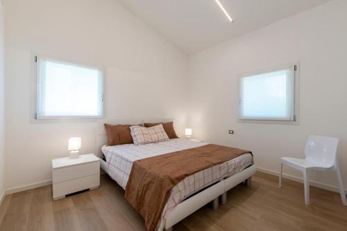 a white bedroom with a bed and a white chair at Serraglia Guest House in San Trovaso