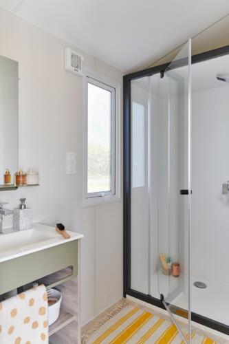 a bathroom with a glass shower and a sink at Camping Saint Laurent in Ploemel