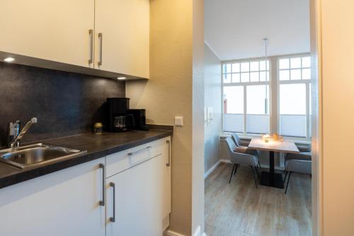 a kitchen with a sink and a table with chairs at Woge2 Appartement 1 in Borkum