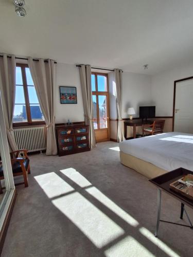 a bedroom with a bed and a desk and windows at Manoir Du Cunningham in Saint Malo