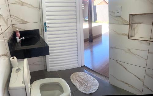 a bathroom with a white toilet and a sink at Casa com área de lazer tranquila e espaçosa! in Campo Grande