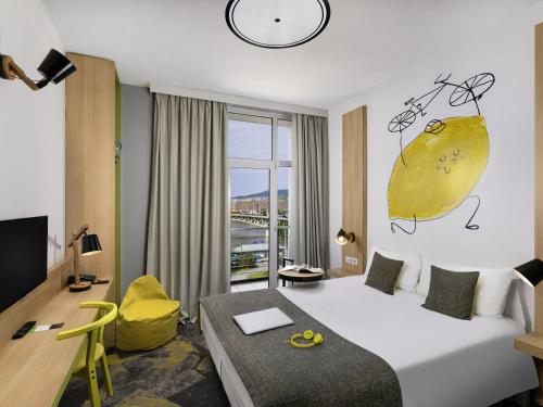 a hotel room with a large bed and a desk and a room at Ibis Styles Budapest City in Budapest