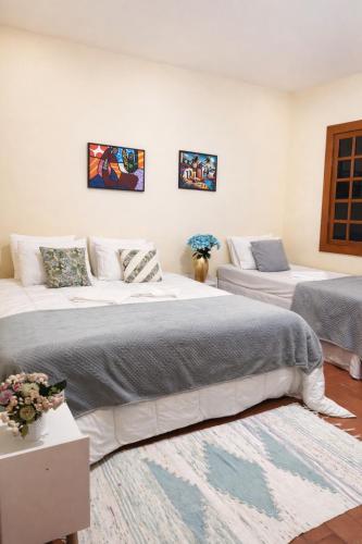 a bedroom with two beds and a rug at Hospedaria Casa dos Coqueiros in Itabirito