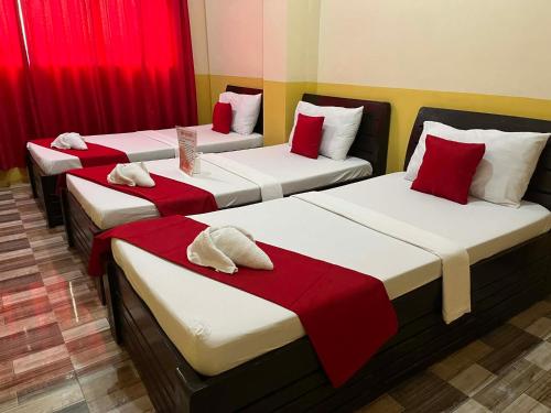 three beds in a room with red curtains at RTRoss Hotel in Masbate