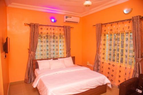 a bedroom with orange walls and a bed with white sheets at Classic Hills Hotel & Resort in Uyo