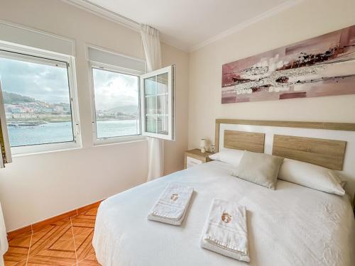 a bedroom with a bed with two towels on it at Apartamento Brisa by ALÔGA in Corcubión