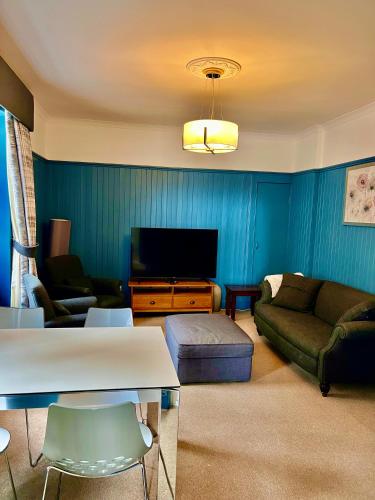 a living room with a couch and a tv at Old Spittal Hospital Apartment - Free Parking in Stirling