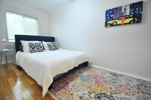 a white bedroom with a bed and a rug at The Austin Cool Condo in Austin
