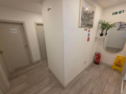 a hallway with a white wall and wooden floors at Zesty Zen in Thornton Heath
