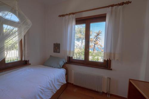 a bedroom with a bed and two windows at Dual bay views by ΜΡS in Dhaskalión