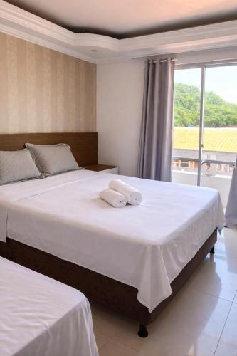 a bedroom with two beds with white sheets and a window at Litorânea Top View ' Beira Mar ' 15 Hospedes in São Luís