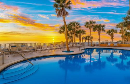 a swimming pool with palm trees and a sunset at Splash Resort Luxury Pools Lazy River Water Parks Sept still Available in Panama City Beach