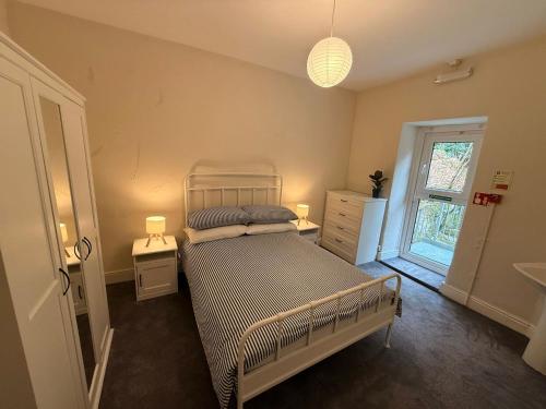a bedroom with a bed and two lamps and a window at 1 Bron Rhedyn Holiday Cottage in Betws-y-coed