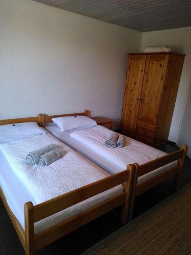two twin beds in a room with a wooden cabinet at Zimmer 12 in Gomadingen