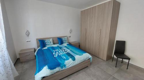 a bedroom with a bed with blue sheets and a chair at La Pineta, 26 - 5 in Casarza Ligure