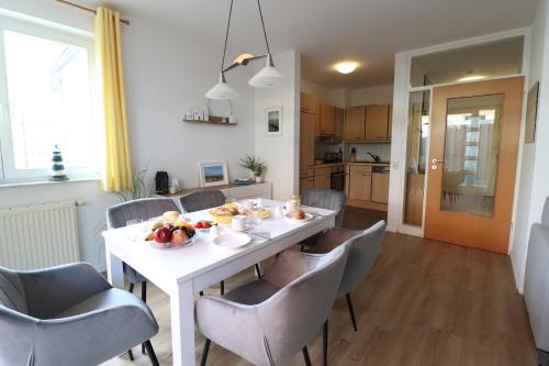 a dining room with a white table and chairs at Meeresrauschen 03 in Neuhaus
