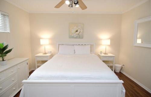 a white bedroom with a white bed with two night stands at Stylish Austin Condo in Austin
