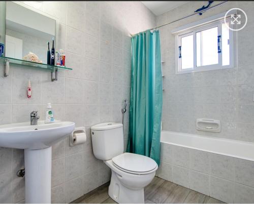 a bathroom with a toilet and a sink and a shower at Newly Renovated Light House Beach 8 min in Paphos