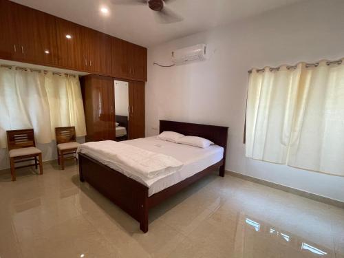a bedroom with a bed and two chairs in it at Santhosh Villa in Thanjāvūr