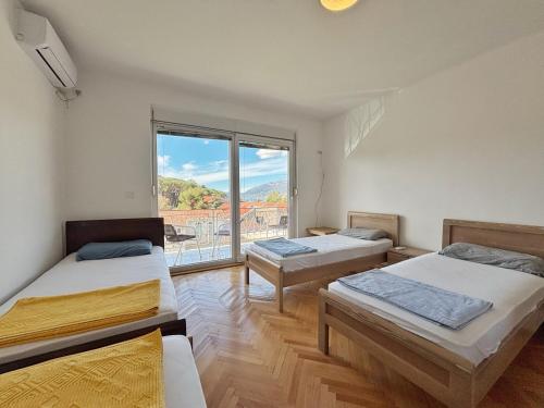 a room with three beds and a large window at Vega's in Tivat