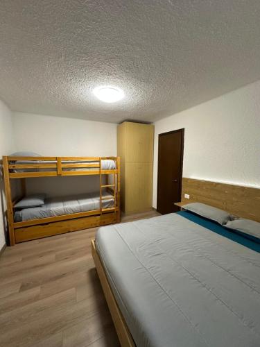 a room with a bed and two bunk beds at Piazzetta Montecampione in Pian Camuno