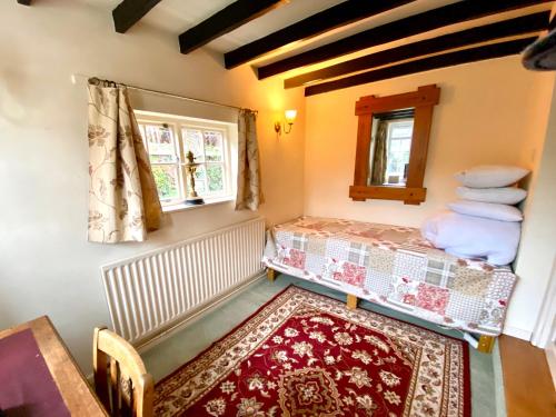 a bedroom with a bed and a window and a rug at Butterfly Cottage in Knowle