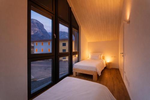 a bedroom with two beds and a large window at Valdastico Short Rentals in Maso