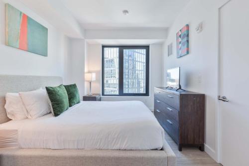 a bedroom with a bed and a dresser and a window at Seaport Retreat - Rooftop Pool & Gym in Boston