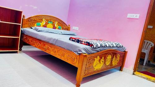 a bedroom with a wooden bed in a pink wall at Sri Seshadri Rest House in Avanigadda