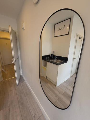 a mirror reflecting a bathroom with a sink and a counter at The Brigstock Nest in Thornton Heath