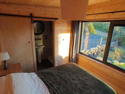 a bedroom with a bed and a large window at The Perch - Romantic Cabin with Sunset Views in Gurteenulla