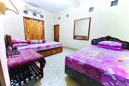 a room with two beds and a mirror at Penginapan Barokah in Kemadang