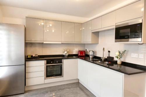 a kitchen with white cabinets and a stainless steel refrigerator at Paradigm House, Delightful 2-Bedroom Flat 4, Oxford in Oxford