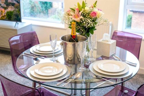 a glass table with plates and a vase of flowers at Paradigm House, Delightful 2-Bedroom Flat 4, Oxford in Oxford