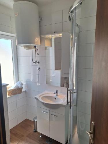 a white bathroom with a sink and a shower at Apartments Dalmacija in Podstrana