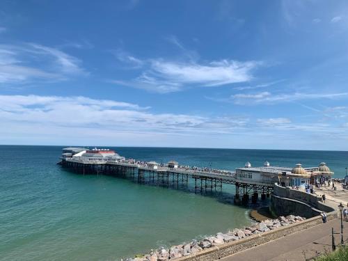 a pier on the ocean with people walking on the beach at Charming Cottage and Beach Hut in Cromer