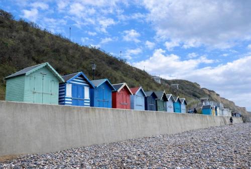 a row of colorful beach huts on a hill at Charming Cottage and Beach Hut in Cromer