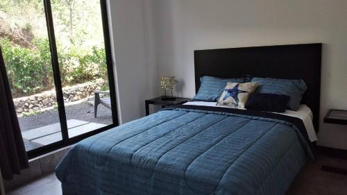 a bedroom with a bed with a blue comforter and a window at Ocean View House, Modern, Elegant with Pool in Coco