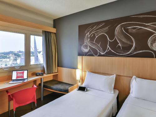 a hotel room with two beds and a desk with a laptop at ibis Goiânia in Goiânia