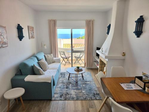 a living room with a blue couch and a table at Casa Salema Praia Clube in Salema