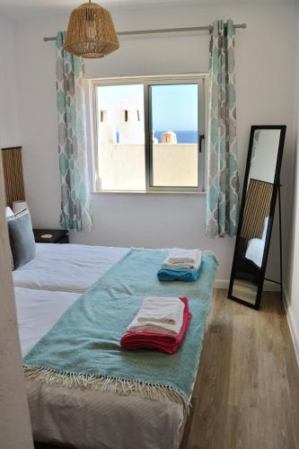 a room with two beds with a window and towels at Casa Salema Praia Clube in Salema