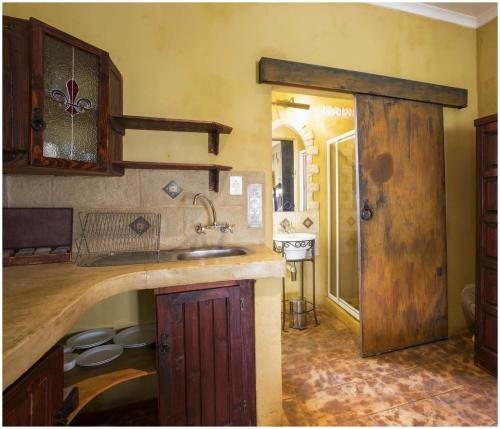 a kitchen with a sink and a wooden door at De Ark Guest House in Lydenburg