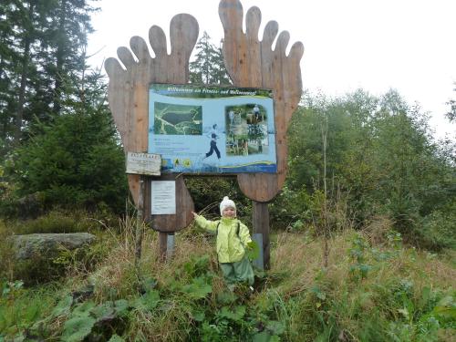 a young child standing in front of a sign at Blockhaus-Bärnkopf in Bärnkopf