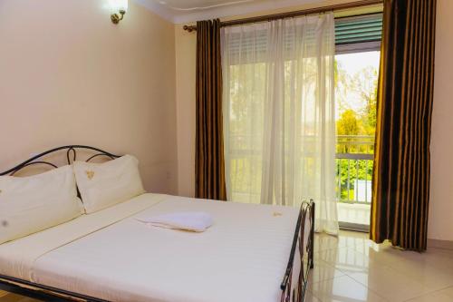 a bedroom with a bed and a large window at Premier motel in Bushenyi