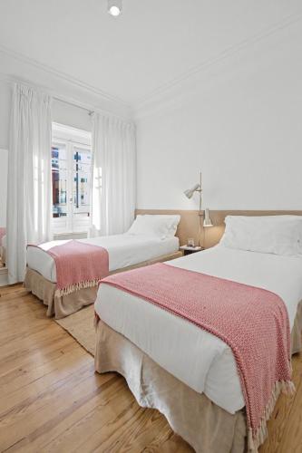 two beds in a white bedroom with a window at Flattered to be in Lisboa in Lisbon