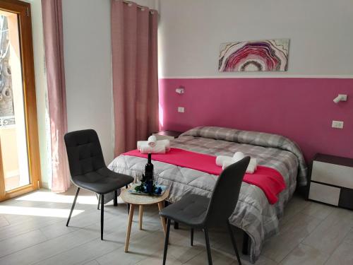 a bedroom with a bed with two chairs and a table at CASA DEL CORSO in Dorgali