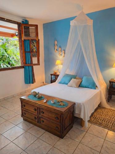 a bedroom with a canopy bed and a wooden table at De l'îlet au Volcan in Basse-Terre