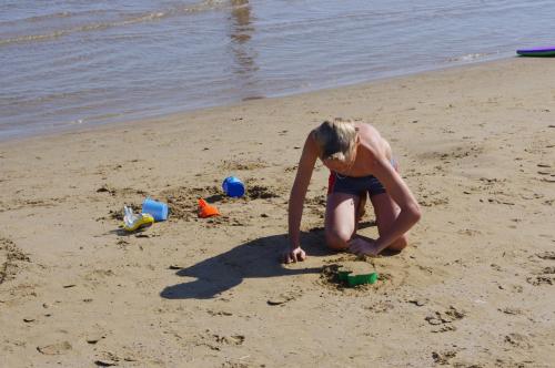 a woman playing in the sand on the beach at Baia Degli Aranci Suite & Apartments in Vieste